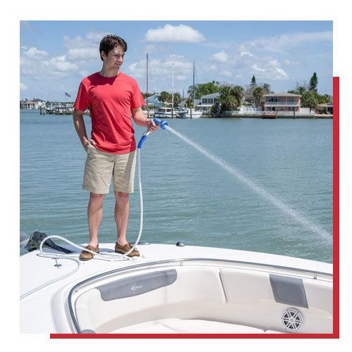 Man spraying boat with hose