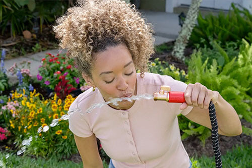 woman drinking from hose