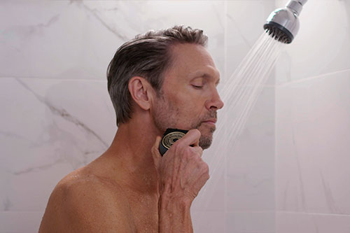 man shaving face in shower