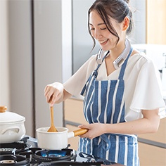 Young woman stirring a pot on the stove